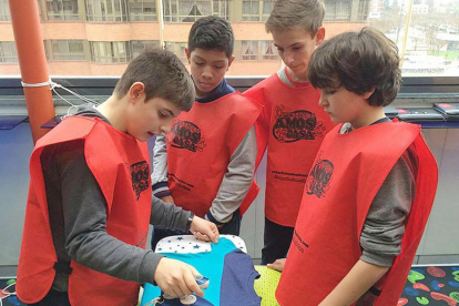 Cuatro niños ataviados con petos rojos forman un equipo y realizan la tarea de plancha.-ECB