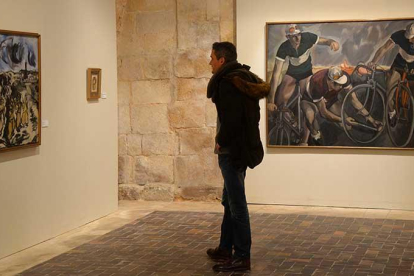 Un visitante observa una de las pinturas y da la espalda a esta imagen de ciclistas que hacía más de setenta años que no se mostraba.-Ricardo Ordóñez (ICAL)
