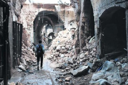 Un miliciano camina por entre las ruinas que han dejado los bombardeos en el zoco antiguo de Alepo, una ciudad habitada desde hace 7.000 años.-AFP / ZEIN AL RIFAI