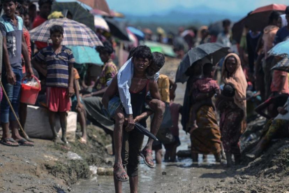 Un joven refugiado rohingya lleva a cuestas un hombre mayor en una zona cercana al lado bangladesí de la frontera con Birmania, tras cruzar el río Naf, el 17 de octubre.-AFP / MUNIR UZ ZAMAN