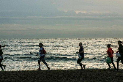 Miembros de Barcelona Plogging, al amanecer en la Barceloneta. Antes de correr, te dan una bolsa biodegradable y un par de guantes. La próxima quedada es el 7 de noviembre.-JOAN CORTADELLAS