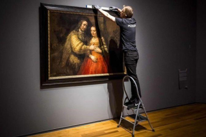 Unos operarios del Rijksmuseum cuelgan La novia judía, de Rembrandt, para la exposición que el museo dedica al artista en el 350 aniversario de su muerte.-AFP / LEX VAN LIESHOUT