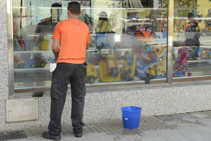 Imagen de un trabajador limpiando un escaparate.-ISRAEL L. MURILLO