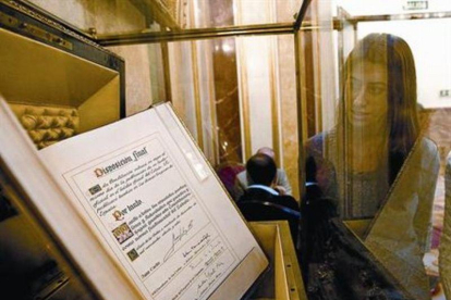 Una empleada del Congreso de los Diputados contempla, ayer, el ejemplar único del texto original de la Constitución, firmado por el Rey y los presidentes de las dos cámaras legislativas durante la sesión solemne que tuvo lugar el 27 de diciembre de 1978.-JUAN MANUEL PRATS