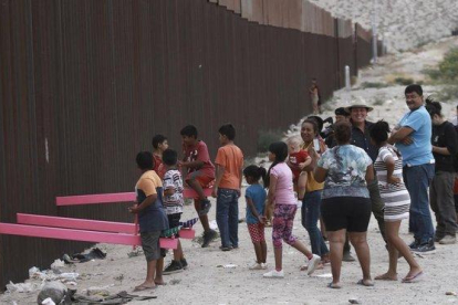 Niños juegan en un balancín situado en el muro de México a su paso por Ciudad Juarez.-CHRISTIAN CHAVEZ (AP)