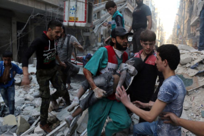 Un hombre saca el cadáver de un niño de una casa alcanzada por un bombardeo en Alepo.-AMEER ALHALBI / AFP