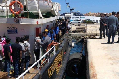 Varios inmigrantes rescatados en alta mar se disponen a desembarcar en el puerto italiano de Lampedusa.-ELIO DESIDERIO (EFE)