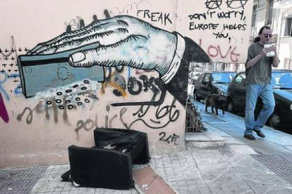 Un hombre pasa ante un grafiti de denuncia en la ciudad de Atenas, este lunes.-Foto: EL PERIÓDICO