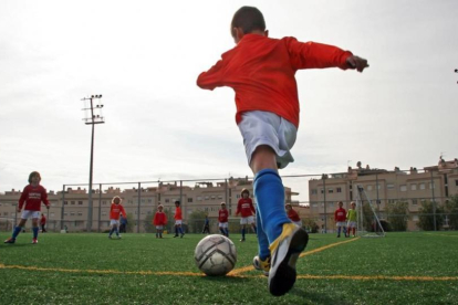 Un niño se apresta a chutar durante un partido de fútbol base.-