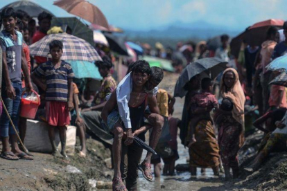 Un refugiado rohinyá lleva a cuestas a un anciano en Bangladés, cerca de la frontera con Birmania.-MUNIR UZ ZAMAN (AFP)