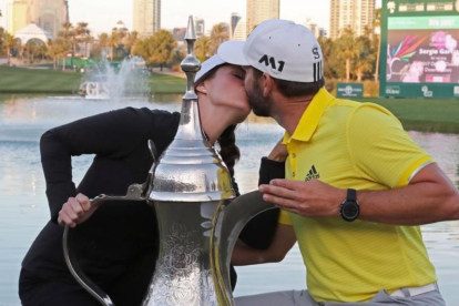 Sergio García besa a su novia, Angela Ankins, junto al trofeo del Omega Dubai Desert Classic.-AFP / KARIM SAHIB