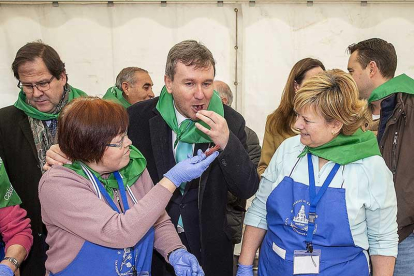 Dos de las voluntarias dan de probar la cecina al alcalde.-SANTI OTERO