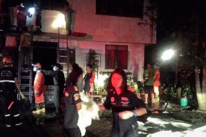 Los bomberos y policías tailandeses recuperan los cadáveres de las niñas fallecidas en el incendio del colegio.-STR