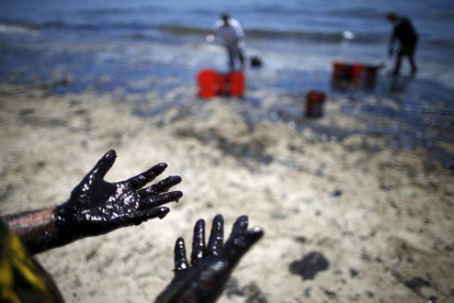Voluntarios cargan cubos de petróleo de las costas de Santa Bárbara.-Foto: REUTERS / LUCY NICHOLSON