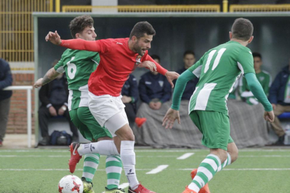 El jugador del Real Burgos Javi pugna por un esférico con dos jugadores de la Cebrereña-Santi Otero