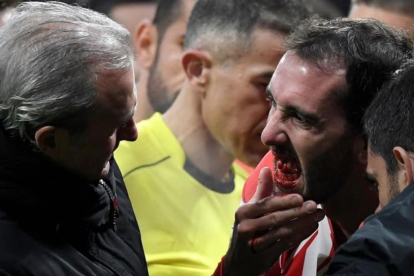 Godín le muestra al doctor del Atlético su boca donde le faltan los tres dientes que acaba de perder en un encontronazo con el meta valencianista Neto.-AFP