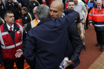 Mourinho y Guardiola se abrazan antes de empezar el derbi de Manchester.-REUTERS / CARL RECINE