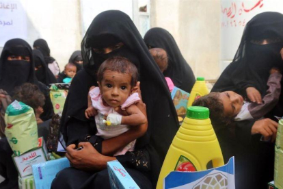 Mujeres yemenís sostienen a sus hijos mientras esperan el reparto de comida en la ciudad de Al Hudayda, en la costa oeste del país.-ABDO HYDER (AFP)