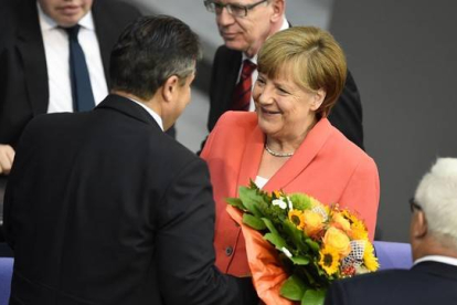 Merkel, felicitada con flores por su 61 aniversario por el vicecanciller, Sigmar Gabriel, en el Bundestag, este viernes.-Foto: AFP / TOBIAS SCHWARZ