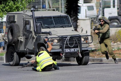 Un palestino, con un chaleco fluorescente y el distintivo de «prensa», acuchilla a un soldado israelí en Hebrón. Los soldados mataron después al agresor.-REUTERS / JAMEEL SALHAB