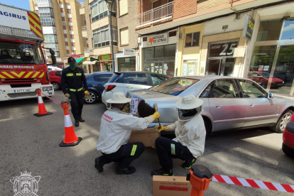 Los especialistas de los bomberos recogiendo las abejas arracimadas en un coche en Gamonal. ECB