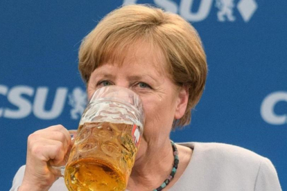 La cancillera alemana bebe una jarra de cerveza tras participar en un mitin en Múnich.-MATTHIAS BALK / AFP