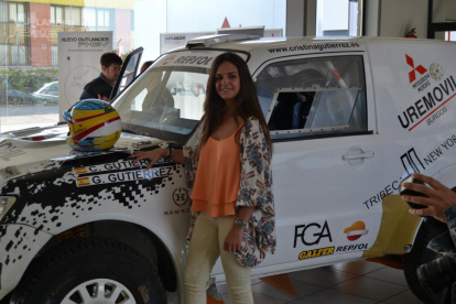 Cristina posa con el coche con el que participó en el certamen. Arriba con las participantes en Doha.-ECB