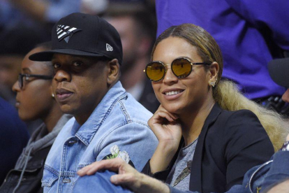 El rapero Jay Z (izq) y su esposa, la cantante Beyonce, asisten a un partido de la NBA.-AP