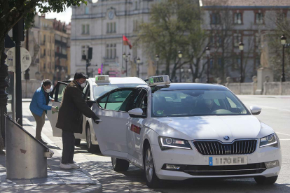 Dos personas mayores con mascarilla abordan sendos taxis en la parada de la plaza del Cid. RAÚL OCHOA