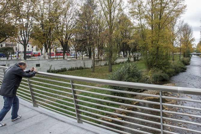 Un hombre hace una foto al río Arlanzón a su paso por la capital burgalesa. ECB