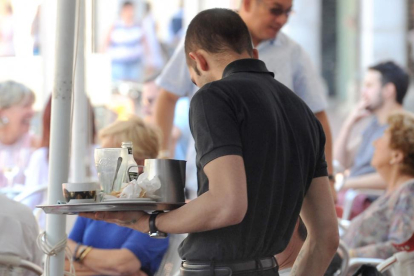 Un camarero atiende a un cliente en una terraza de la ciudad.-ISRAEL L. MURILLO