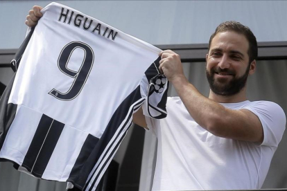 El delantero Gonzalo Higuaín muestra a sus aficionados su nueva camiseta de la Juventus.-MARCO BERTORELLO / AFP