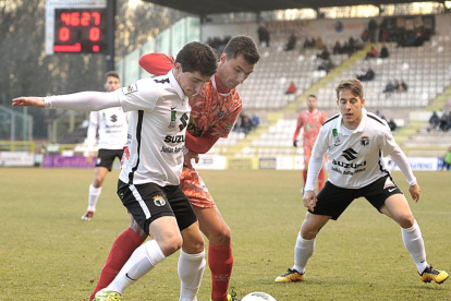 Jorge Fernández protege el balón ante el acoso de un oponente y la atenta mirada de Álvaro Antón.-ISRAEL L. MURILLO