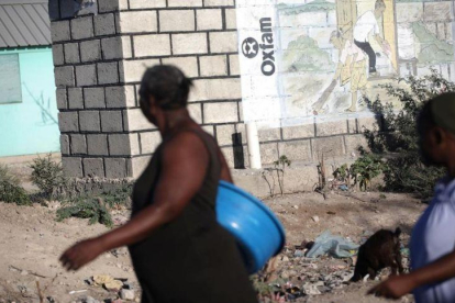 Dos mujeres pasan ante un mural de Oxfam en Puerto Príncipe, Haití.-ANDRES MARTINEZ CASARES (REUTERS)