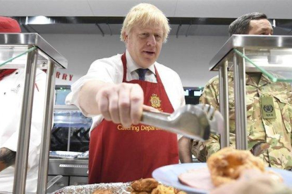 El primer ministro británico, Boris Johnson, sirve el sábado comida de Navidad a las tropas británicas estacionadas en Estonia.-AP / STEFAN ROUSSEAU