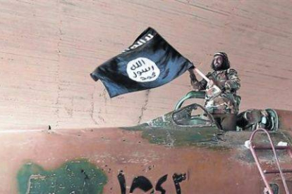 Un militante del Estado islámico ondea una bandera del califato en Raqqa (Siria).-Foto: AP