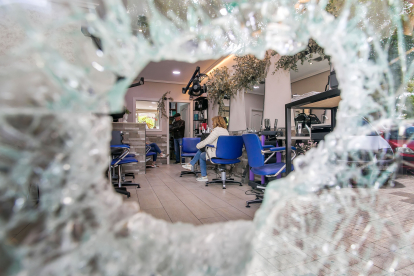 Interior de la peluquería Nati visto a través del agujero que dejaron los ladrones en el cristal de la puerta.