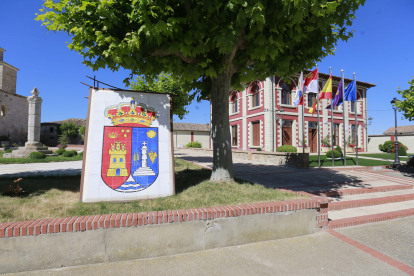 Escudo de la localidad, con el ayuntamiento al fondo.