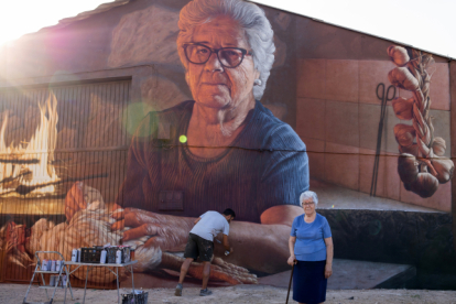 Christian Sasa trabaja en el mural con su protagonista delante.