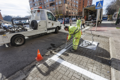 Operarios pintan el aparcamiento de motos  junto a un paso de la calle Condesa Mencía.