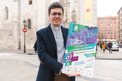 Diego Mingo, vicario parroquial de San Cosme y San Damián, muestra el cartel del Cross Urbano a favor de los enfermos de ELA.