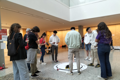 Un grupo de participantes prueban las habilidades de su robot para tirar las latas fuera del círculo.