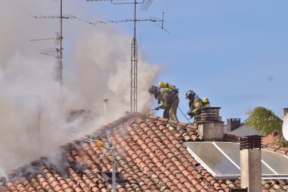 Dos bomberos intervienen desde la cubierta del edificio.