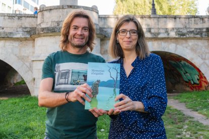 Jairo Marcos y María Ángeles Fernández, con un ejemplar de 'Memorias ahogadas', en el río Arlanzón, junto al puente San Pablo.