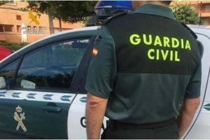 Archivo - Un agente y un coche de la Guardia Civil.