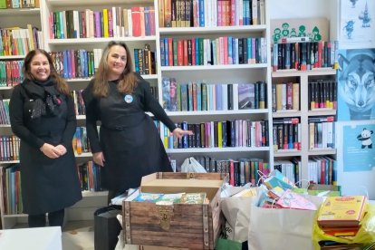 Arantzazu Suances y Sylvia Cernadas, las libreras de La Silla Mágica, con el material donado que llenaba el escaparate y parte de su librería.