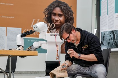 Una exhibición de fabricación de herramientas de piedra, de fondo TIAGo, el robot de PAL Robotics que ya puede responder a un problema fabricando su herramienta para resolverlo.
