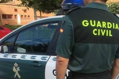 Archivo - Imagen de archivo de un agente de la Guardia Civil ante un coche patrulla.
