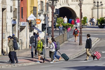 Turistas con maletas en la plaza de Vega, en las cercanías de la estación de autobuses y el Arco de Santa María y la Catedral.