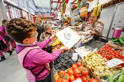 Un alumno del colegio Virgen de la Rosa entrega una de las bolsas de tela a una comerciante del mercado Norte provisional.